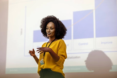 A woman delivering a presentation on industry insights with visual aids on screen