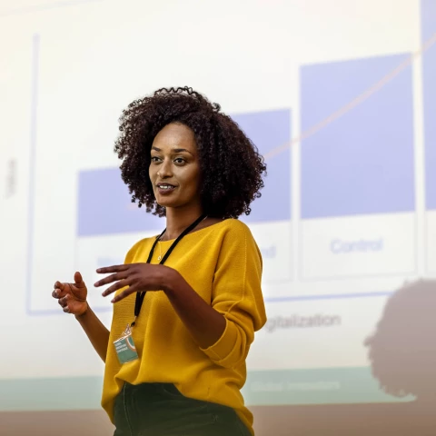 A woman delivering a presentation on industry insights with visual aids on screen