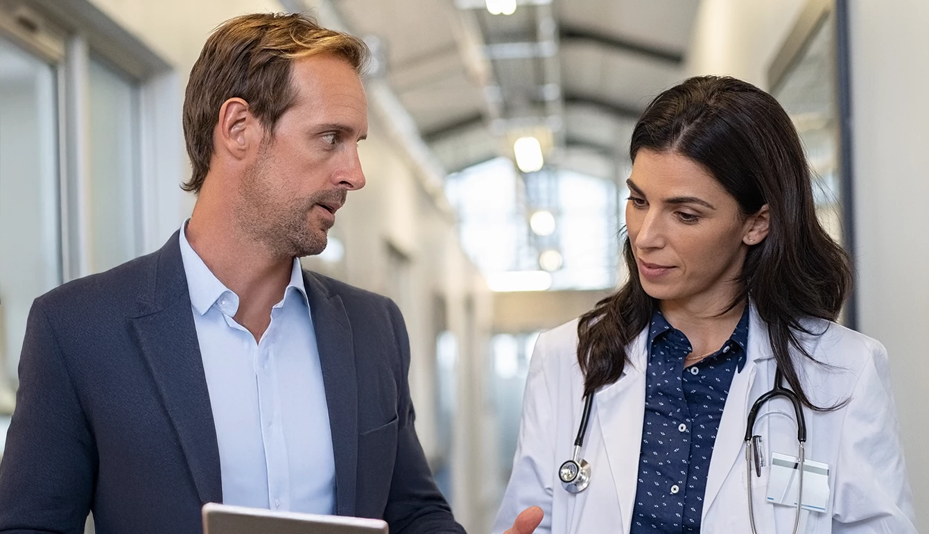 A man and woman converse in a hospital hallway