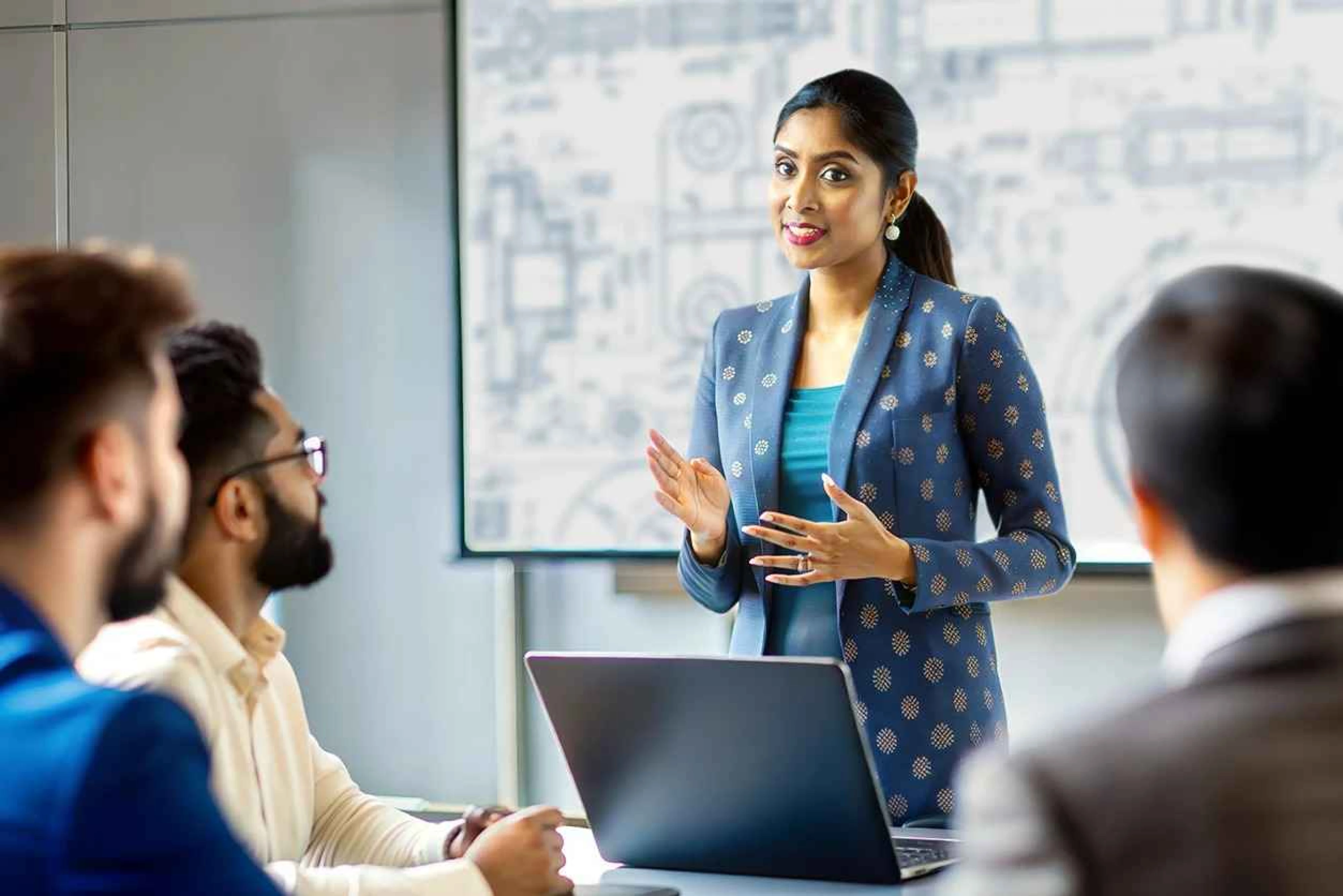 A woman in a business suit presents to an audience in San Jose, CA