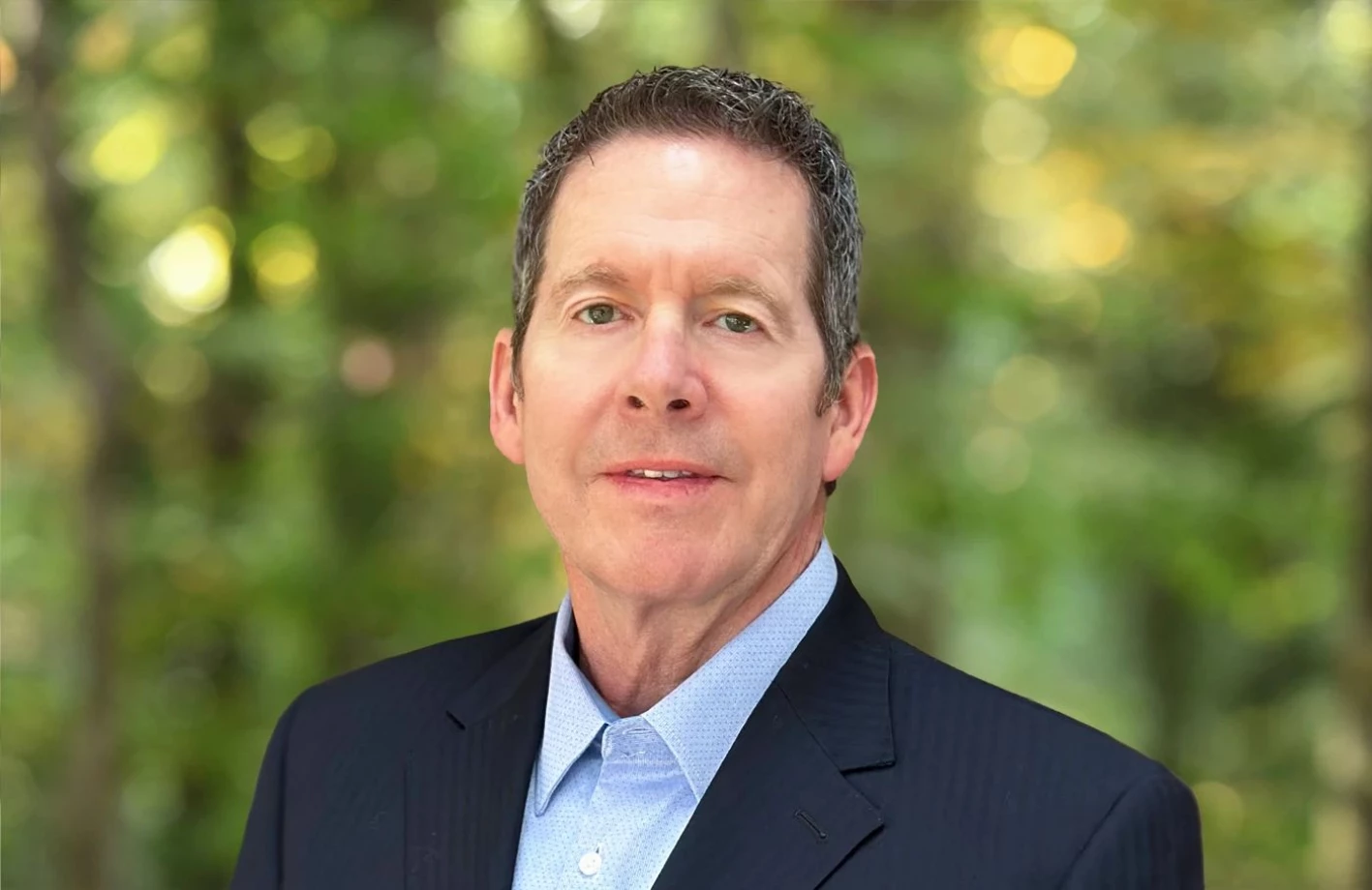 Kevin Geoghegan, Solution Advisor stands in front of trees in a suit and tie at IMS Legal Strategies