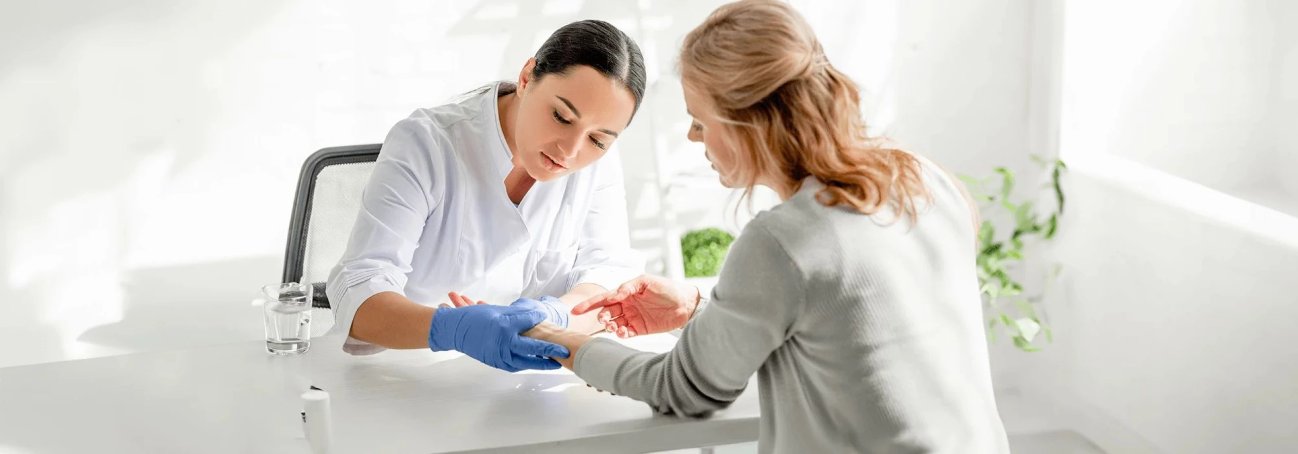 A woman in a white shirt discusses dermatology with another woman, emphasizing IMS legal strategies